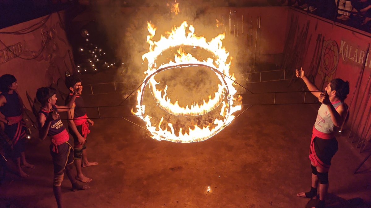 A Kalaripayattu performer leaping through a ring of fire during a Kalari show near Munnar