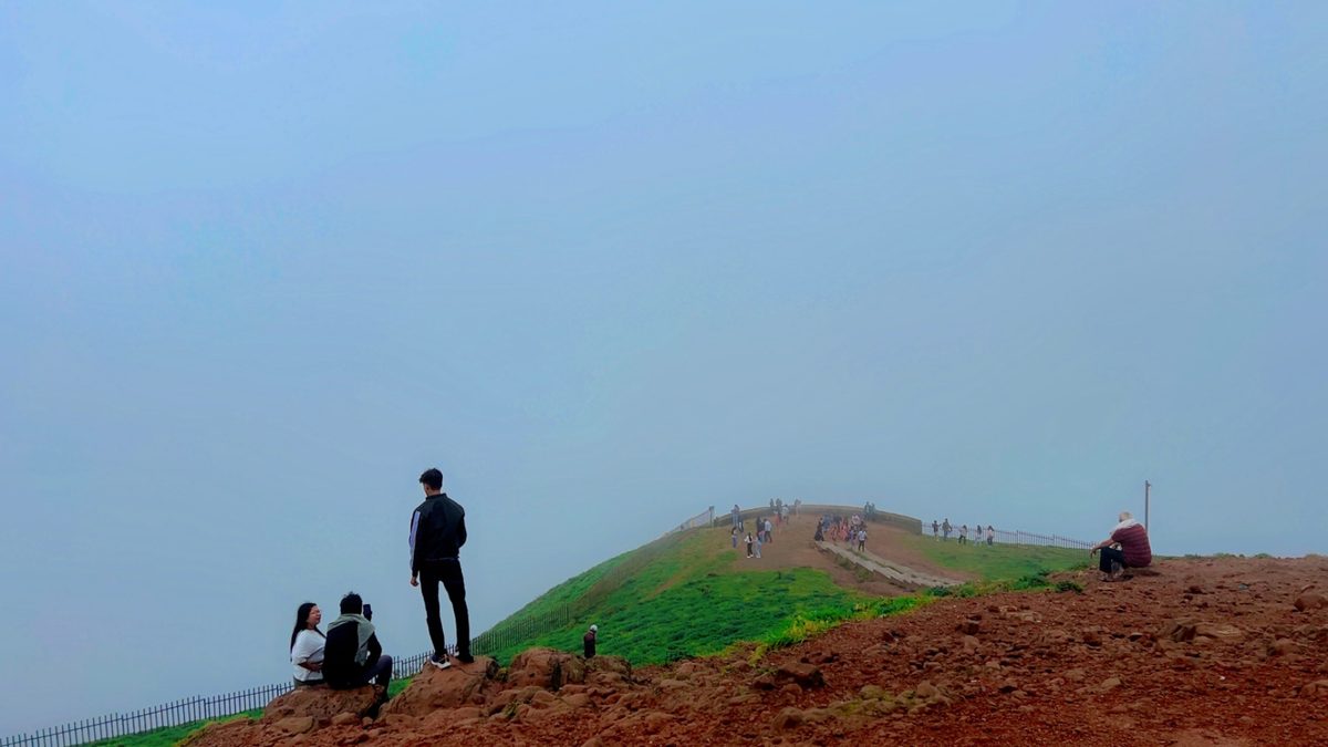 Visitors on the misty green ridge of Mandalpatti Peak in Coorg
