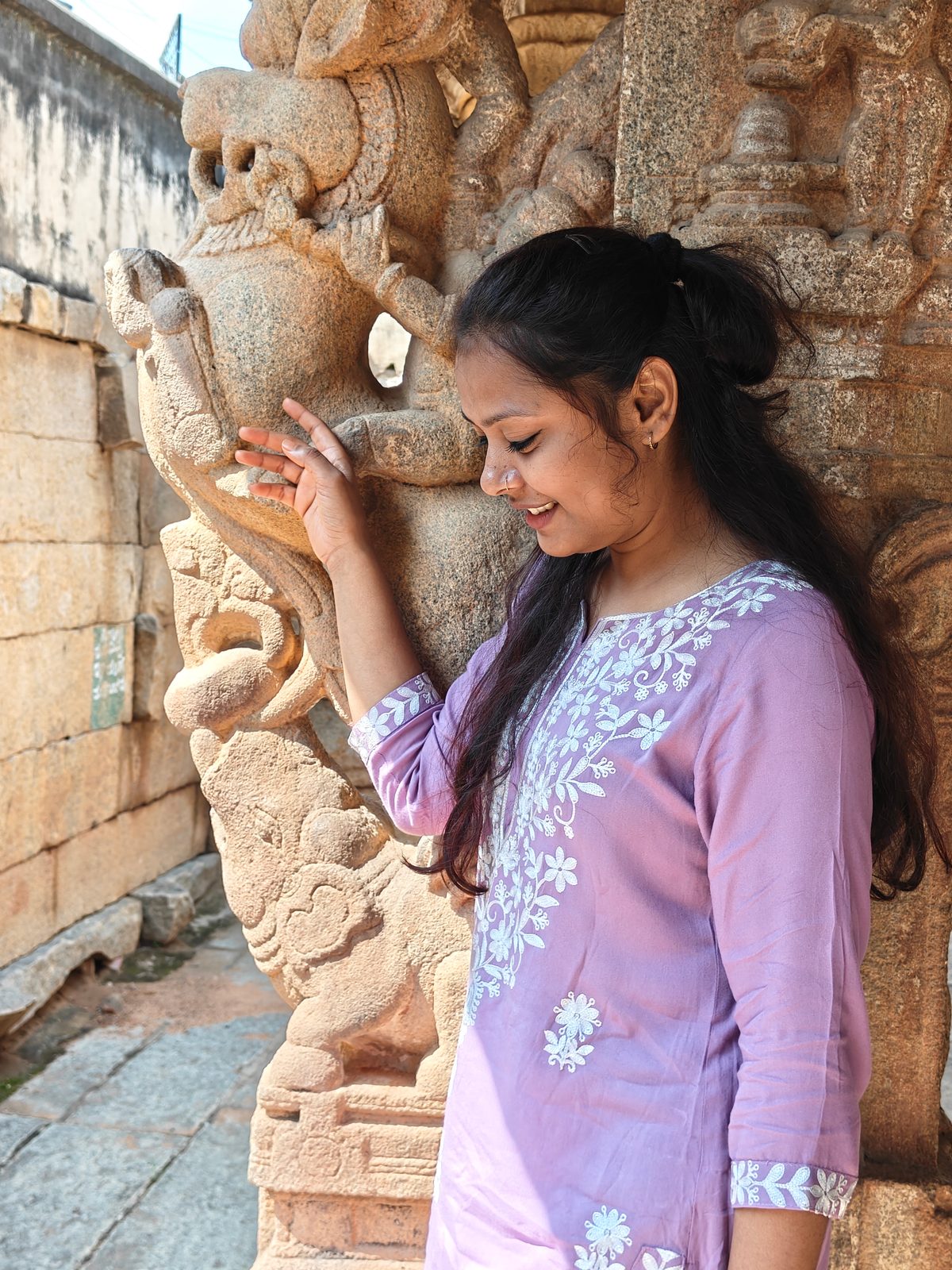 A traveller examining the detailed stone carving on a temple pillar in Kolar